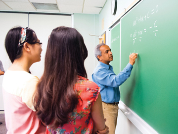 students watching professor write on blackboard