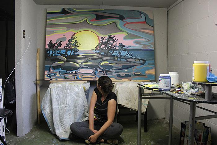 student sitting looking back at painting of landscape