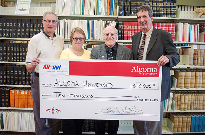 officials standing with large cheque for ten thousand dollars