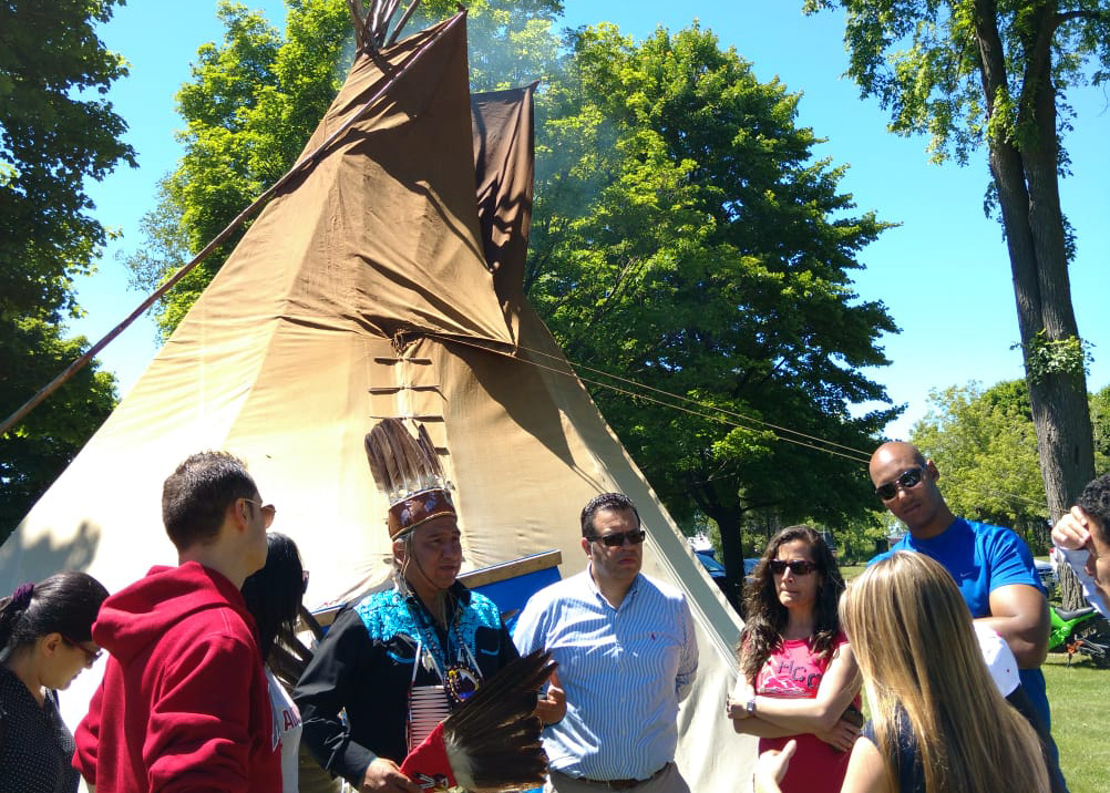 students speaking with chief next to a tipi