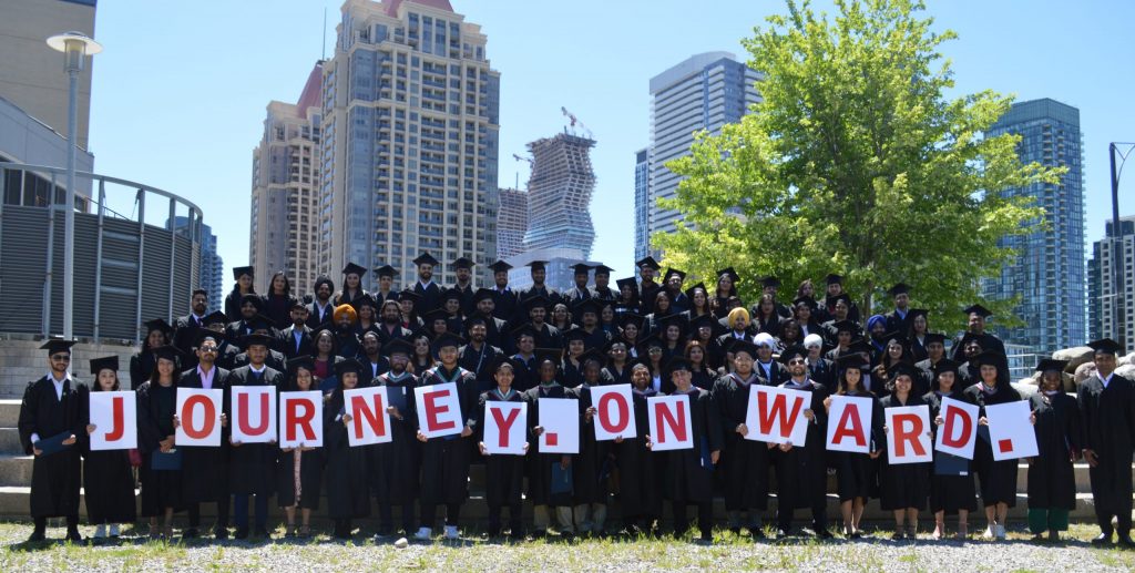 Graduates holding "Journey Onward" signage