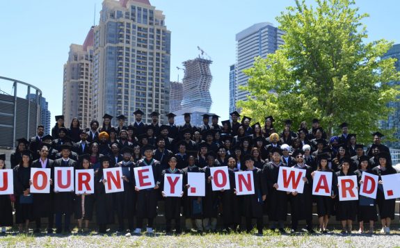 Graduates holding "Journey Onward" signage