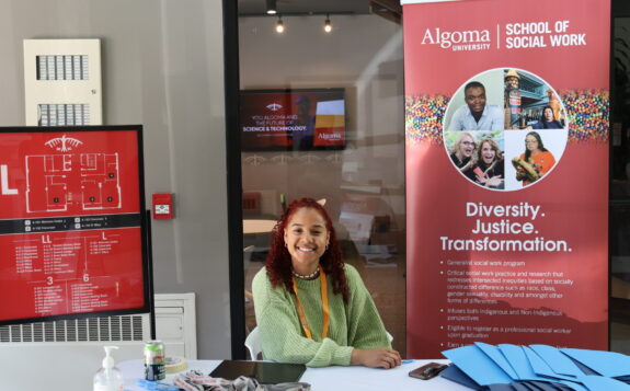 Student sitting at a desk in front of a banner